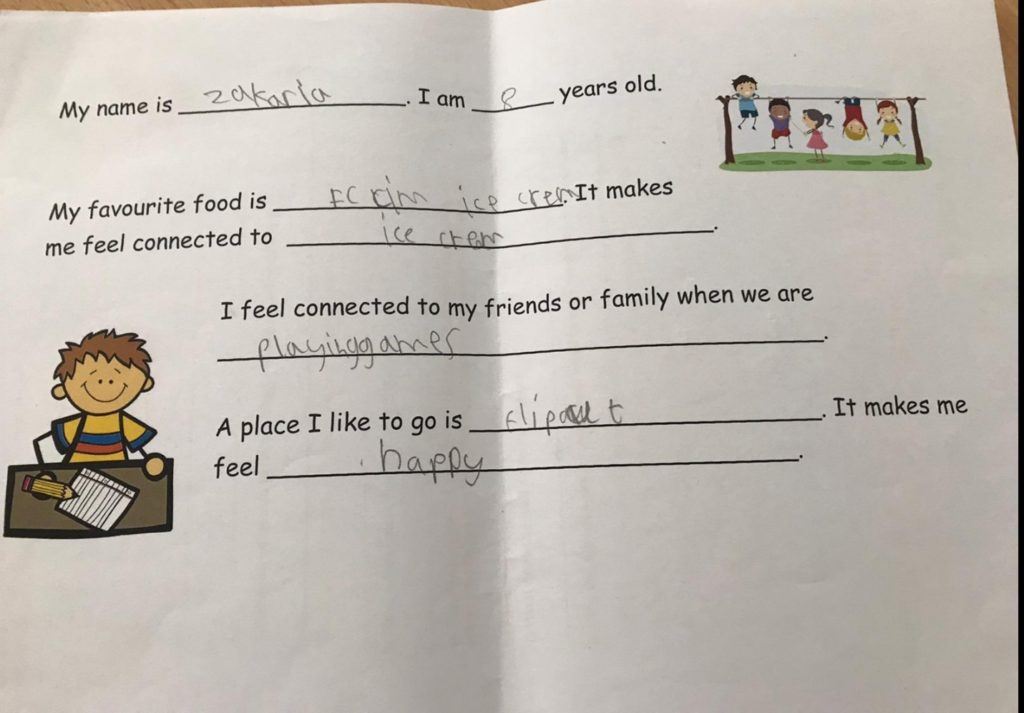 Photo of a worksheet with cartoon of kids playing and a boy sitting at a desk.  Text reads:  "My name is Zakaria. I am 8 years old. My favourite food is ice cream. It makes me feel connected to ice cream.  I feel connected to my friends or family when we are playing games.  A place I like to go is Flip It. It makes me feel happy."
