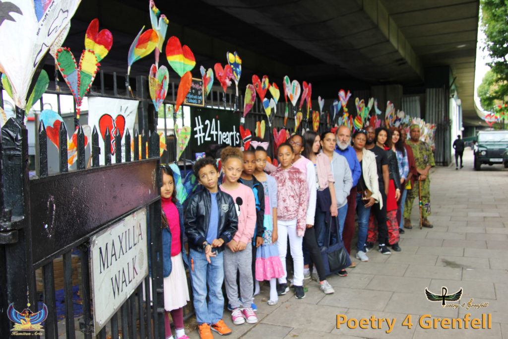 Photo of a group of adults and children on Maxilla Walk outside railings which are covered in decorated hearts. 