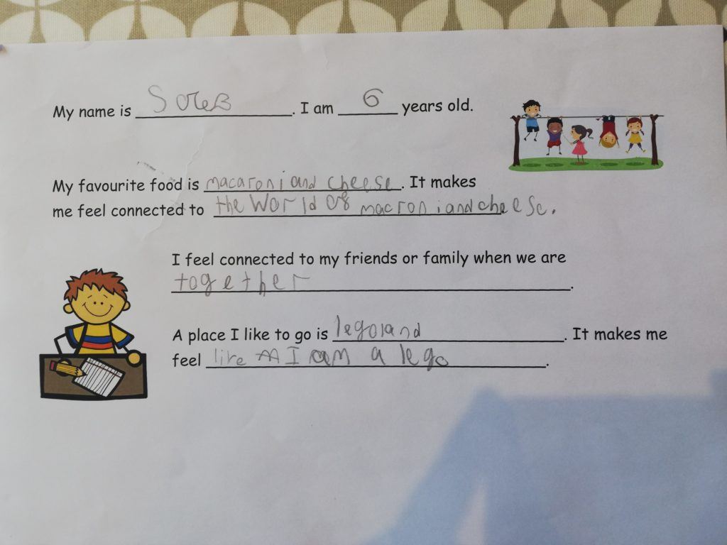 Picture of a worksheet with smiling children playing in the playground and sitting at a desk.  Words say:
"My name is Sole. I am 6 years old.  My favourite food is macaroni and cheese. It makes me feel connected to the world of macroni and cheese. I feel connected to my friends or family when we are together.  A place I like to go is legoland. It makes me feel like I am a lego."